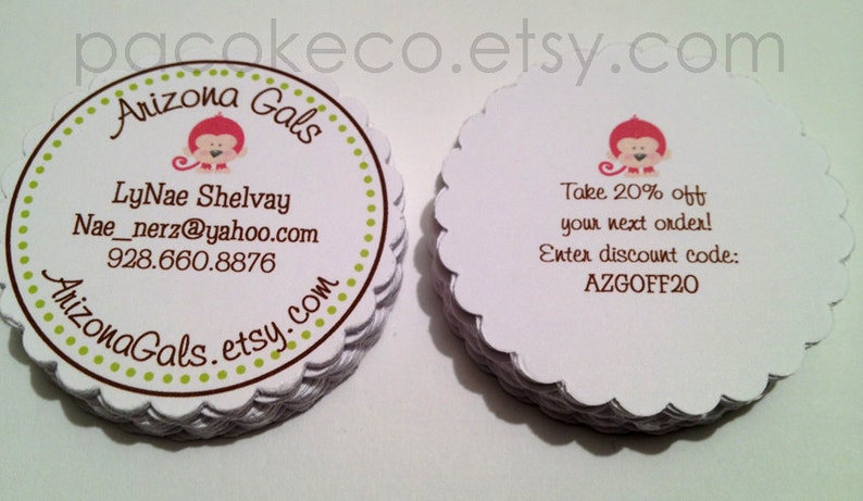May include: White, scalloped-edge business cards stacked. One card features a monkey graphic and business details: Arizona Gals, LyNae Shelvay, email, and phone number. Another card offers a 20% discount with code AZGOFF20.