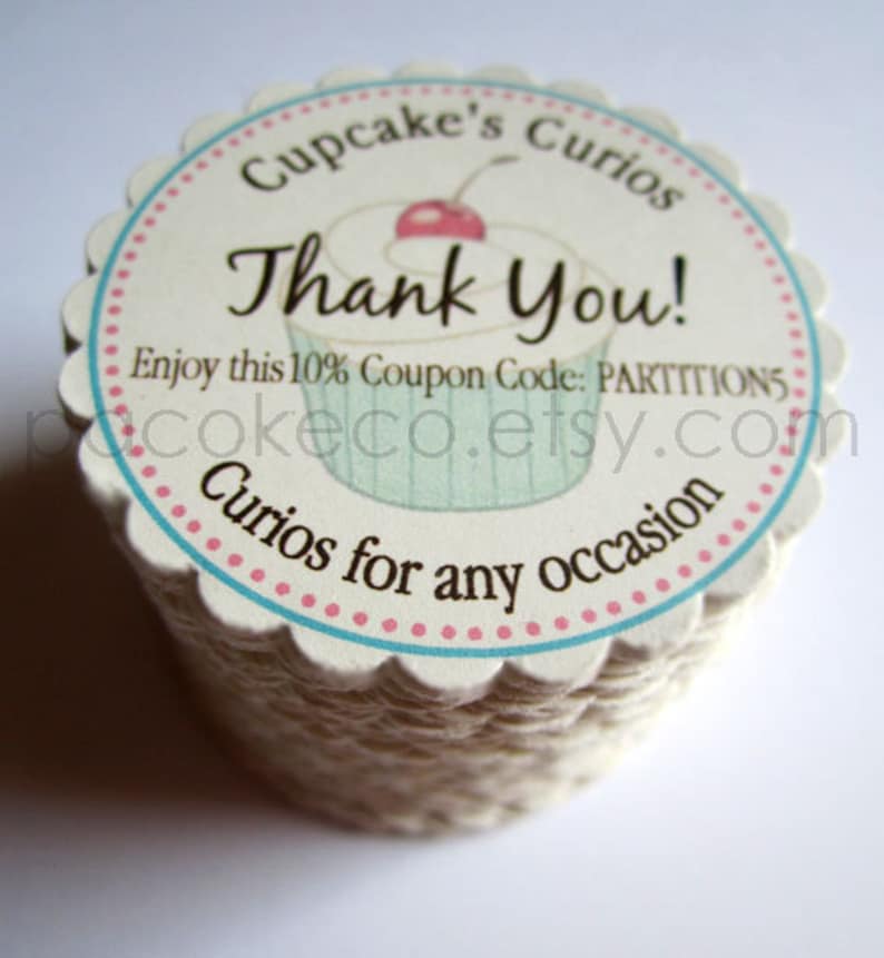 May include: A stack of cupcake-shaped tags with a scalloped edge. The tags feature a cupcake illustration and the words "Thank You!" in a script font. Text includes "Cupcake's Curios" and "Curios for any occasion."