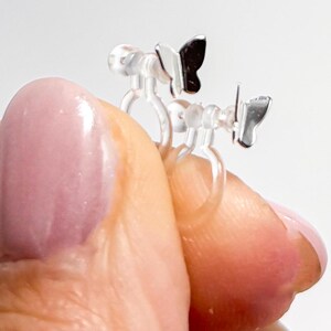 May include: A pair of clear plastic butterfly ear clips with silver butterfly charms. The clips are designed to be worn without piercing.
