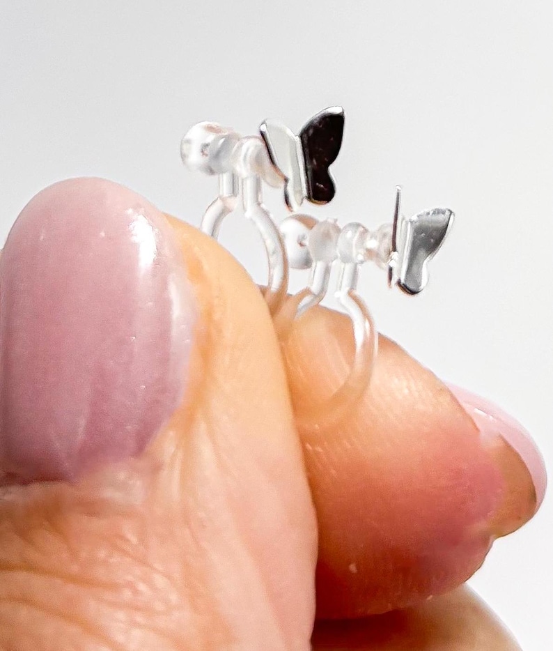May include: A pair of clear plastic butterfly ear clips with silver butterfly charms. The clips are designed to be worn without piercing.