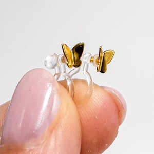 May include: A pair of gold butterfly earrings with clear plastic ear clips.