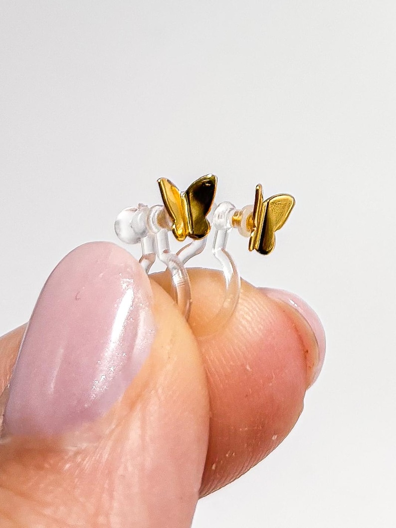 May include: A pair of gold butterfly earrings with clear plastic ear clips.