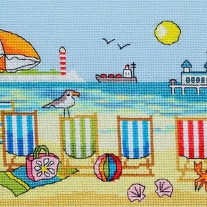 Puede incluir: Un patrón de punto de cruz colorido que representa una escena de playa con sillas de playa, una sombrilla, un muelle y un faro. Las sillas de playa están rayadas en rojo y blanco, azul y blanco, y verde y blanco. La sombrilla es naranja y blanca. El muelle es blanco con un techo a rayas rojas y blancas. El faro es rojo y blanco. La playa es amarilla y el agua es azul.