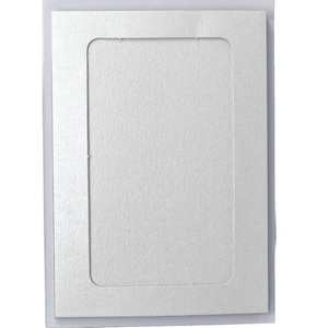 Puede incluir: Un paspartú rectangular blanquecino con una abertura rectangular. Se presenta dentro de una funda de plástico transparente. El paspartú tiene una superficie texturizada y un brillo sutil.