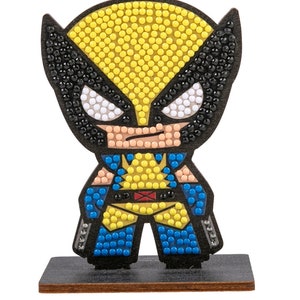 May include: A yellow, blue and black diamond painting of a cartoon superhero character with a black mask. The character is standing on a black wooden base.