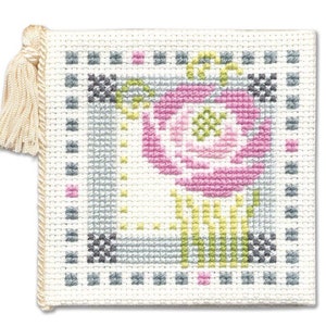 May include: A white needlepoint cushion with a pink and green floral design. The cushion has a tassel on one corner.
