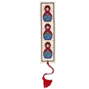 May include: A white bookmark with a red tassel. The bookmark features three embroidered Russian nesting dolls in red, blue and white.