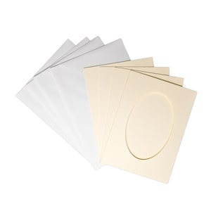 Puede incluir: Un conjunto de paspartús blancos y crema. Los paspartús crema tienen un recorte ovalado. Los paspartús están dispuestos en forma de abanico, con los blancos a la izquierda y los crema a la derecha.