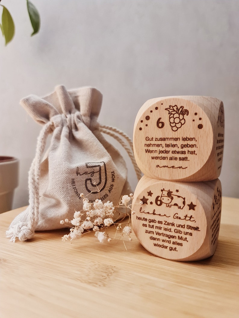 Puede incluir: Dos bloques de madera con dichos e ilustraciones grabados. El bloque superior tiene un racimo de uvas y el texto "Gut zusammen leben, nehmen, teilen, geben. Wenn jeder etwas hat, werden alle satt. amen". El bloque inferior tiene una vaca y el texto "lieber Gatt, heute gab es Zank und Streit. es tut mir leid. Gib uns zum Vertragen Mut, dann wird alles wieder gut."