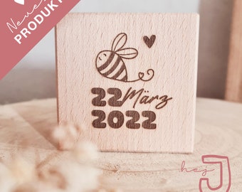 Puede incluir: Un bloque de madera con un diseño de abeja y corazón, y el texto "22 März 2022".