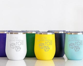 Puede incluir: Seis vasos de acero inoxidable en diferentes colores, incluyendo morado, blanco, verde, amarillo, negro y azul. Cada vaso tiene el texto "Let the good times roll" y un gráfico de dos dados.