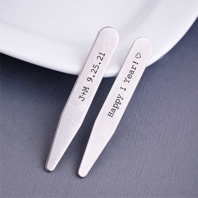 May include: Two silver collar stays with engraved text. One stay reads "J+M 9.25.21" and the other reads "Happy 1 year!" with a heart symbol.