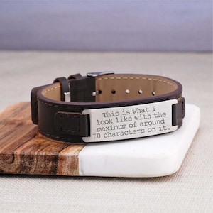 May include: A brown leather bracelet with a silver metal plate engraved with the text: "This is what I look like with the maximum of around 70 characters on it."