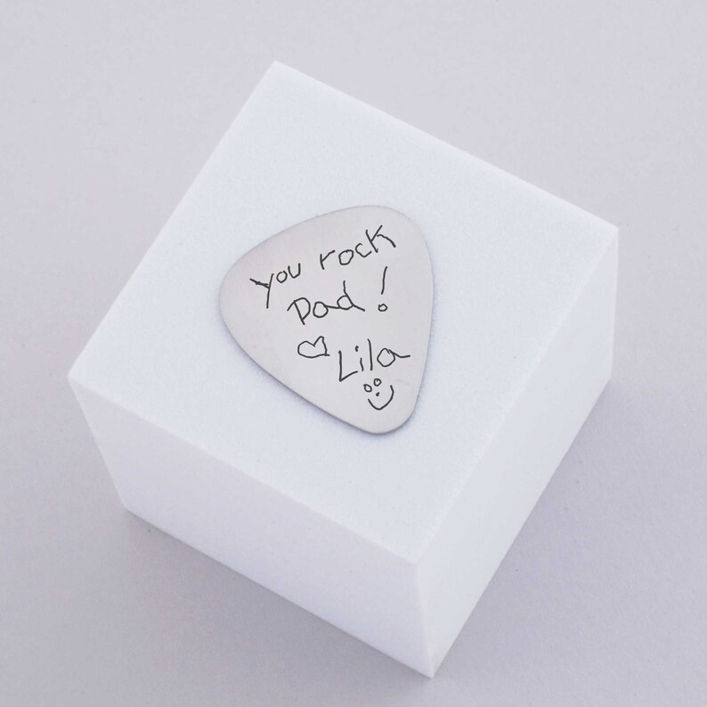 stainless steel guitar pick engraved with the handwritten message saying you rock dad!  heart symbol Lila and a smiley face