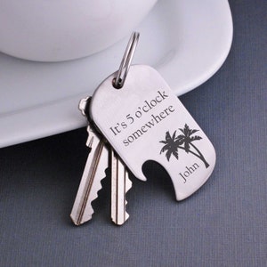 May include: Silver keyring with a bottle opener and palm tree design. It says "It's 5 o'clock somewhere" and "John".