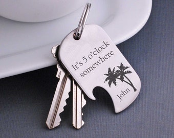 May include: Silver keychain with a bottle opener and palm tree design. It says "It's 5 o'clock somewhere" and "John".