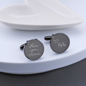 round cufflinks in gunmetal color showing handwritten words love you more on one and heart kate on the other