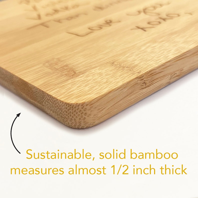 May include: Close-up of the edge of a light brown, rectangular bamboo cutting board. The board is about 1/2 inch thick.  The text "Love you" is engraved on the board.