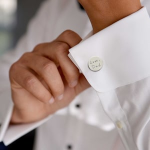 man wearing round stainless steel cufflinks with handwriting engraved