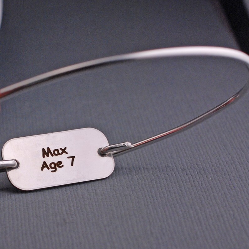 a silver bracelet with a rectangle shaped disc showing back engraving. Recommended back engraving is name and age or a date