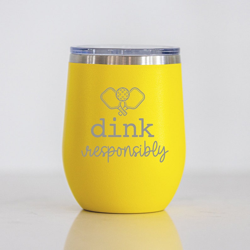 May include: Yellow stainless steel tumbler with a gray graphic of two pickleball paddles and the text "dink responsibly".