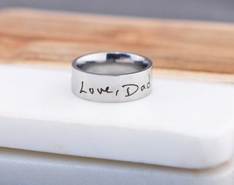 May include: A silver ring with the words "Love Dad" engraved on it.
