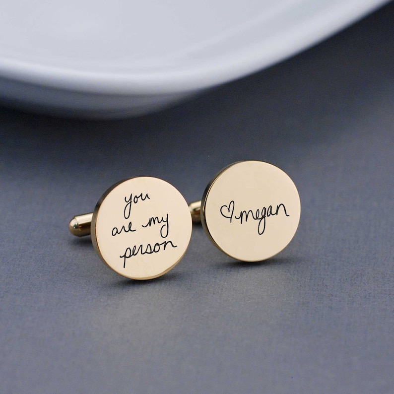 gold round cufflinks with the words you are my person on one and heart megan on the other in handwriting