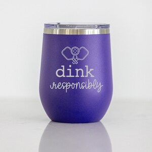 May include: Purple stainless steel tumbler with a white design of two pickleball paddles and a ball. The text "dink responsibly" is also printed in white.