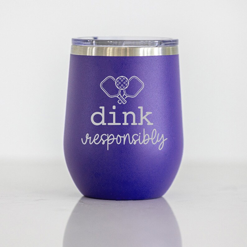 May include: Purple stainless steel tumbler with a white design of two pickleball paddles and a ball. The text "dink responsibly" is also printed in white.