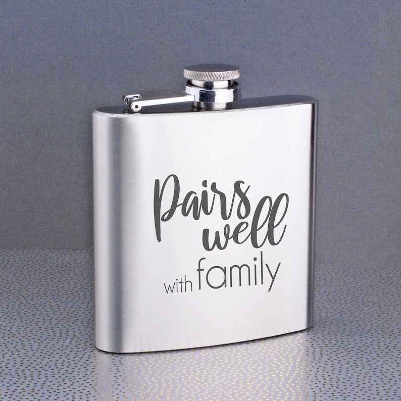 Może przedstawiać: Srebrna stalowa butelka z zakrętką. Na butelce wygrawerowano napis "Pairs well with family".