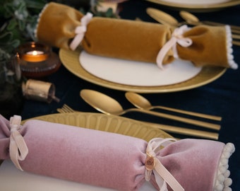 May include: Three velvet Christmas crackers with gold, green, and pink fabric. Each cracker is tied with a ribbon and has a small tag with the initials "HM".