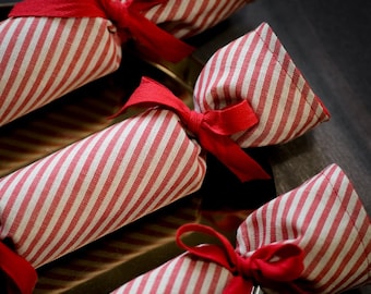 May include: Four red and white striped fabric Christmas crackers with red ribbon bows.