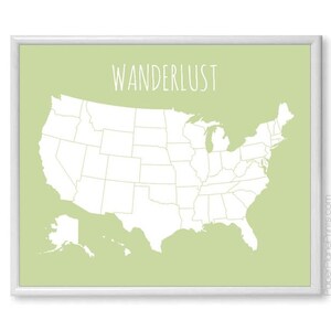 May include: A framed print featuring a map of the United States in white against a light green background. The word "WANDERLUST" is written in a handwritten style font at the top. The print is in a white frame.
