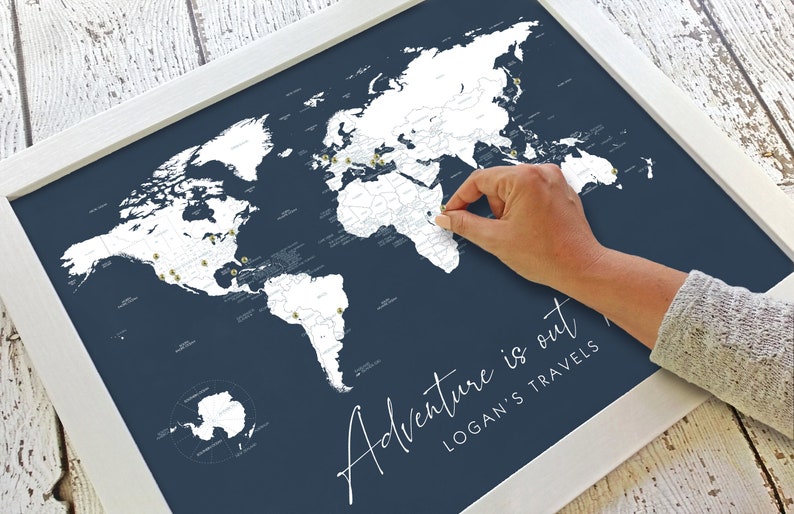 May include: A white world map with gold push pins on a dark blue background. The map is framed in white and has the text "Adventure is out" and "Logan's Travels" written below the map.