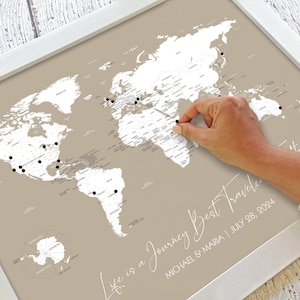 May include: A beige world map with a white frame. The map is designed for marking off places visited with push pins. The text "Life is a Journey Best Traveled" is written in white script at the bottom of the map. The text "MICHAEL & MARIA | JULY 28, 2024" is written in white script below the text "Life is a Journey Best Traveled".