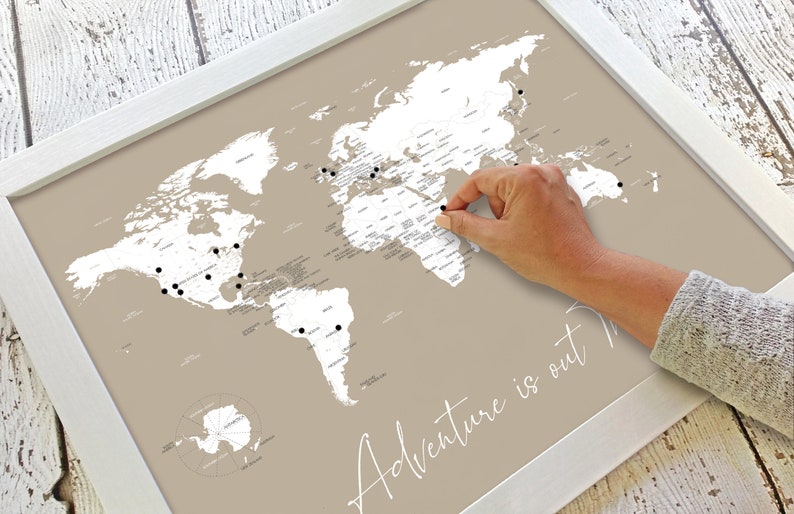 Beautiful decorative couples world push pin map for marking travels and places visited. With script cursive Adventure is out There travel quote title. Shown in neutral taupe beige and customizable to other colors and personalized names and date.