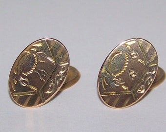May include: A pair of gold oval cufflinks with a floral design.