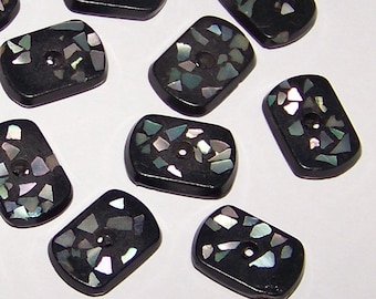 May include: A collection of 20 black rectangular buttons with iridescent, speckled, and mottled designs. The buttons have two holes each.