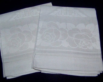 May include: Two white linen hand towels with an embossed rose pattern and a monogrammed "CH" in the upper corner.