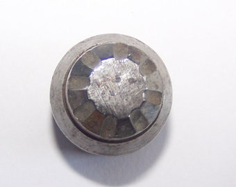 May include: A silver metal button with a starburst design.