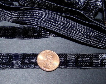 May include: Black ribbon with a textured pattern. A penny is next to the ribbon for size comparison. The ribbon is likely used for crafts, sewing, or gift wrapping.
