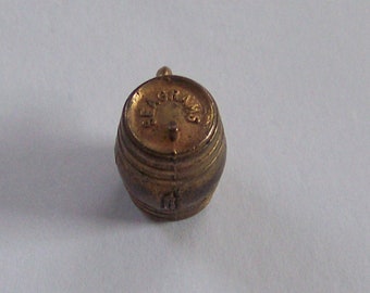May include: A small gold-colored metal barrel with the words "Seagrams" embossed on the top.