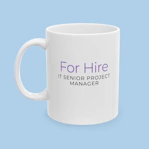 Puede incluir: Taza de café de cerámica blanca con una inscripción morada que dice "For Hire IT Senior Project Manager".