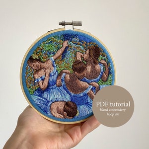 May include: Embroidered hoop art featuring a group of dancers in blue dresses with a green and brown background. The hoop is held in a hand and the text "PDF tutorial Hand embroidery hoop art" is visible in the lower right corner.
