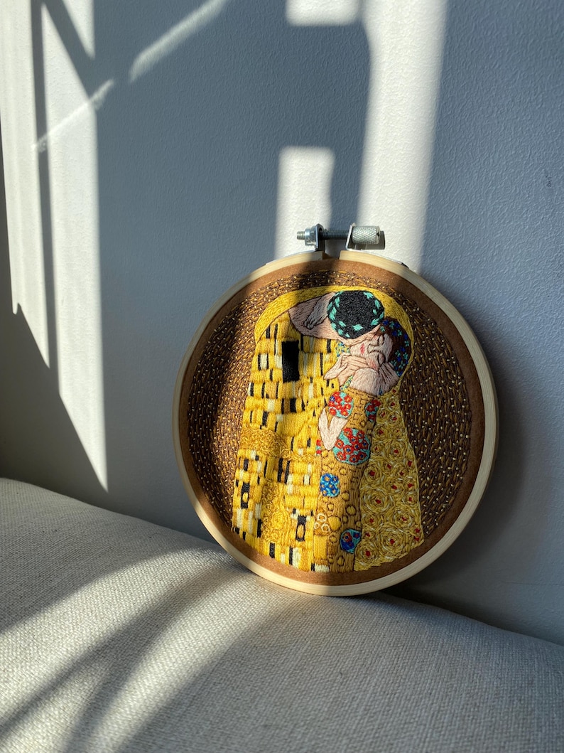 Pu&ograve; includere: Opera ricamata in un cerchio di legno che rappresenta un famoso dipinto di due figure che si baciano. L'opera &egrave; realizzata in stile mosaico con filo giallo, oro e blu.