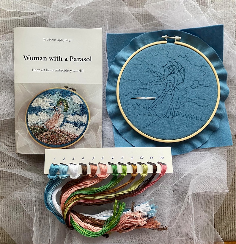 May include: A hand embroidery tutorial for a hoop art project featuring a woman with a parasol. The tutorial includes a printed guide and a set of 12 embroidery floss colors.