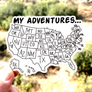 May include: A black and white sticker of a map of the United States with the text "MY ADVENTURES..." at the top. Each state is labeled with its two-letter abbreviation.