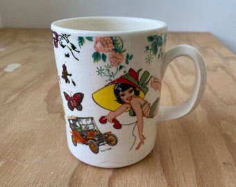 Porcelain mug with decals of pin-up girls and black lab, made on pottery wheel