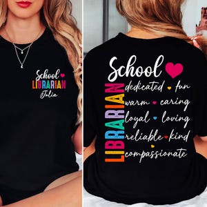 May include: Black t-shirt with the text "School Librarian Julia" in colorful letters. The back of the shirt features the word "School" and the word "Librarian" vertically, along with descriptive words like "dedicated" and "caring".