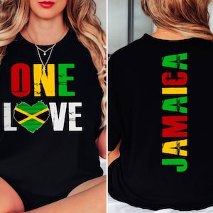 May include: Black t-shirt with the words "ONE LOVE" and a heart-shaped Jamaican flag design on the front. The back of the shirt displays the word "JAMAICA" vertically in green, yellow, and red.